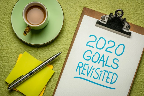 2020 goals revisited  - change of business and personal plans for  coronavirus pandemic and economy recession, handwriting in a clipboard with coffee