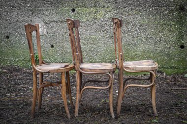 Terk edilmiş beton duvarlı eski ahşap sandalyeler