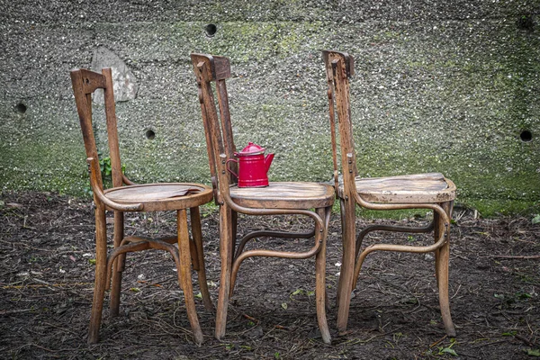 old wooden chairs with an abandoned concrete wall