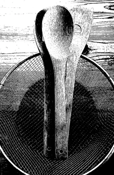 Black and white illustration with high contrast of a group of wooden spoons on a rustic wooden one in a family kitchen