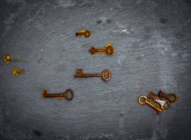 Üzerinde pas izleri olan anahtarlar siyah bir taş zemin üzerinde yukarıdan fotoğraflanmış.
