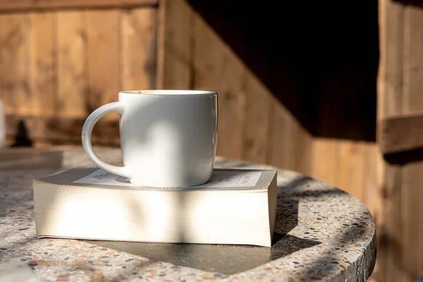 古い素朴な森を背景に古いテーブルの上にカプチーノコーヒーと本と白いカップ — ストック写真