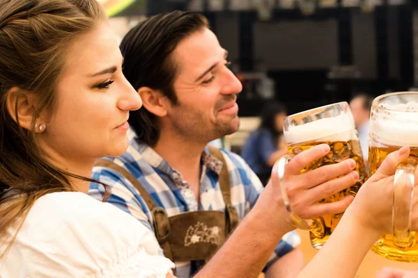 Jovem casal brindar na tenda de cerveja Oktoberfest — Fotografia de Stock