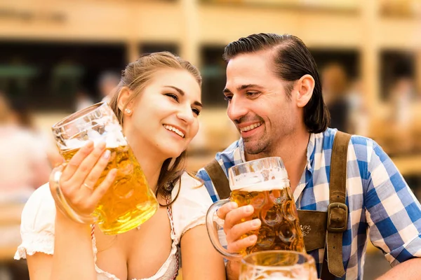 Pareja joven coqueteando en Oktoberfest tienda de cerveza mientras bebe cerveza — Foto de Stock