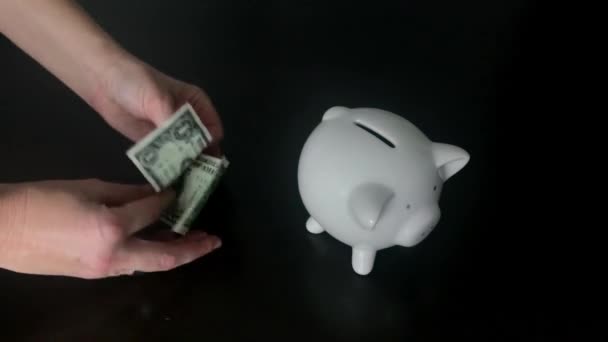 Vrouw een ons Dollar bankbiljet ingebruikneming een piggy bank — Stockvideo