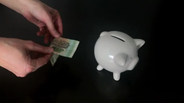 Vrouw een 500 Russische roebels bankbiljet ingebruikneming een piggy bank — Stockvideo