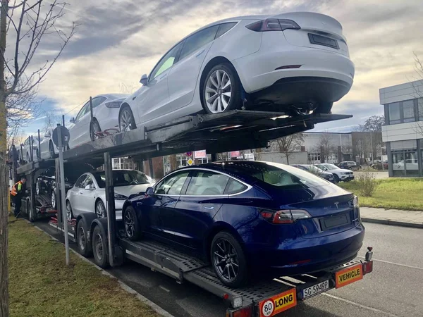 Транспортер має нові транспортні засоби Тесла - в основному модель 3 - поблизу Мюнхенського центру доставки. — стокове фото