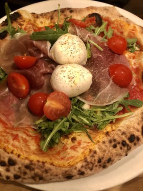 Mozzarella peynirli, jambonlu, domatesli ve roket salatalı İtalyan pizzası.