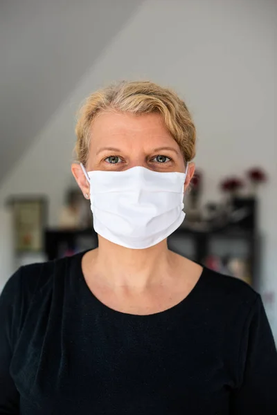 Retrato de una mujer caucásica de mediana edad con una máscara medial contra el virus Corona y la infección en su sala de estar en casa — Foto de Stock