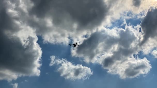 Квадрокоптер он же дрон летит против неба и приземляется на грунтовой дороге — стоковое видео