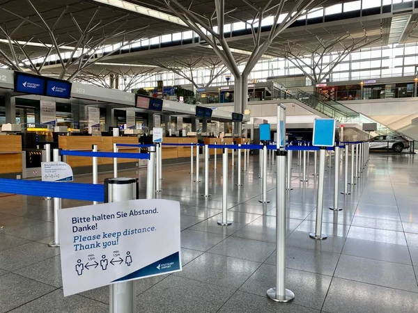 Brote de Coronavirus: Los mostradores de facturación vacíos con recordatorios de seguridad Corona en la terminal del aeropuerto debido a la pandemia de coronavirus y las aerolíneas suspendieron la mayoría de sus vuelos en Stuttgart, Alemania . —  Fotos de Stock