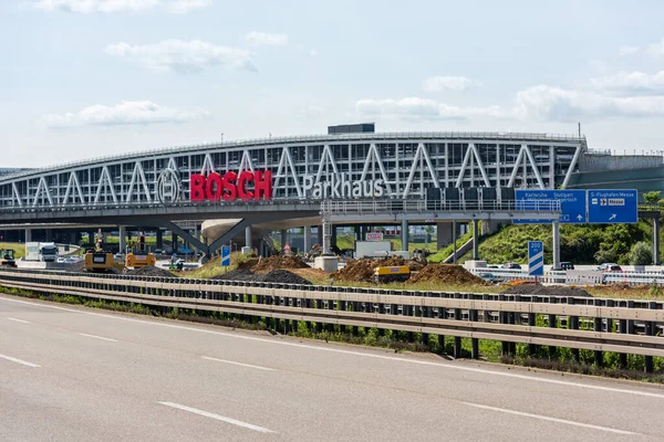 Enormi lettere Bosch al garage dell'aeroporto di Stoccarda con autostrada A8 vuota e lavori di costruzione in primo piano. Bosch è una multinazionale tedesca di ingegneria ed elettronica . — Foto Stock