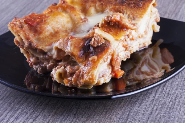 Lasagna fekete tükröző lemez felett — Stock Fotó