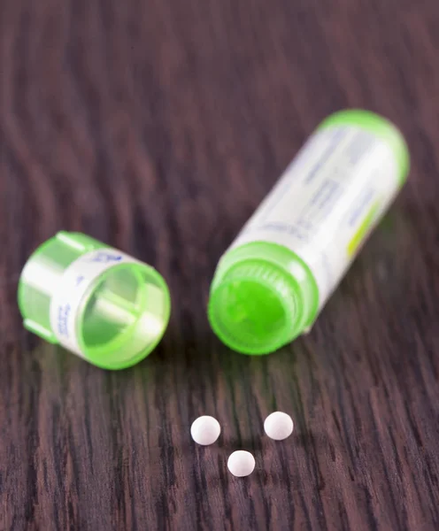 Píldoras homeopáticas sobre mesa de madera — Foto de Stock