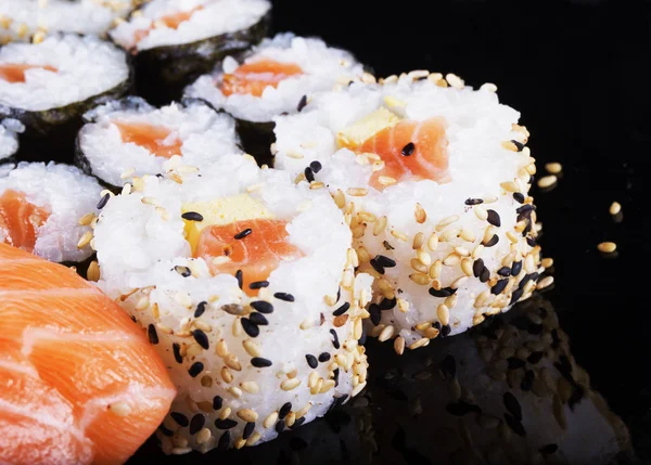 Sushi peças sobre placa reflectora preta — Fotografia de Stock