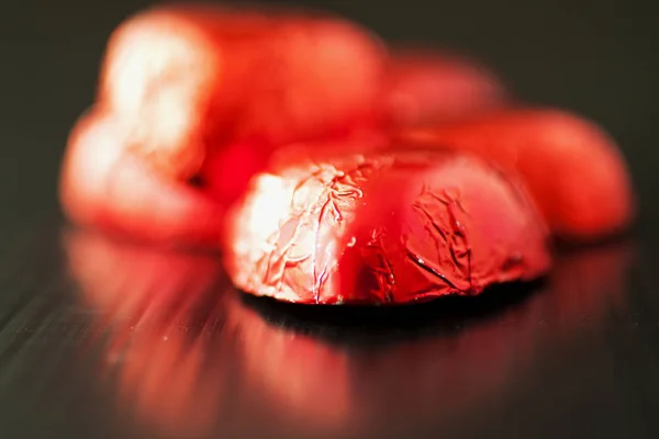 Chocolates em forma de coração sobre a superfície preta refelcting — Fotografia de Stock