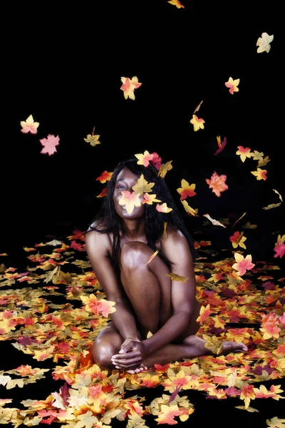 Desnuda implícita mujer afroamericana lanzando hojas de otoño —  Fotos de Stock