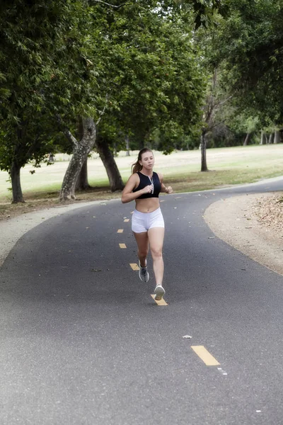 白种人少女女人在公园里的自行车道上运行 — 图库照片