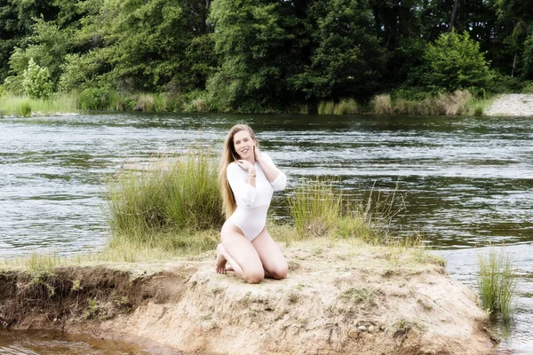 Kaukasische tiener vrouw geknield langs de rivier In witte maillots — Stockfoto