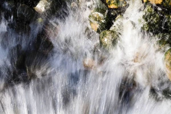 Spruzzatura del flusso d'acqua sulle rocce coperte di muschio — Foto Stock
