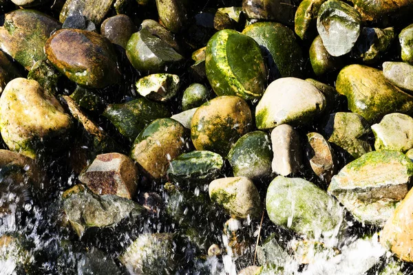 Spruzzi d'acqua su rocce ricoperte di muschio — Foto Stock