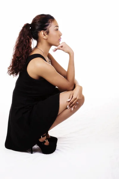 Atraktivní Latina žena v podřepu profil v černých šatech — Stock fotografie