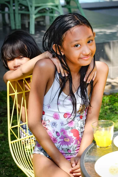 Весела азіатська дівчина-підліток позує разом зі своїм маленьким братом у купальнику на відкритому повітрі — стокове фото