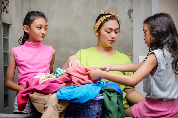 Азійська сім'я побутового побуту. Залишайтеся вдома матір "ю, яка займається пральнею і допомагає своїм дітям — стокове фото