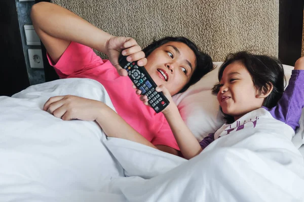 Asiatiska lilla pojken på sängen vill ta över TV Remote Control — Stockfoto
