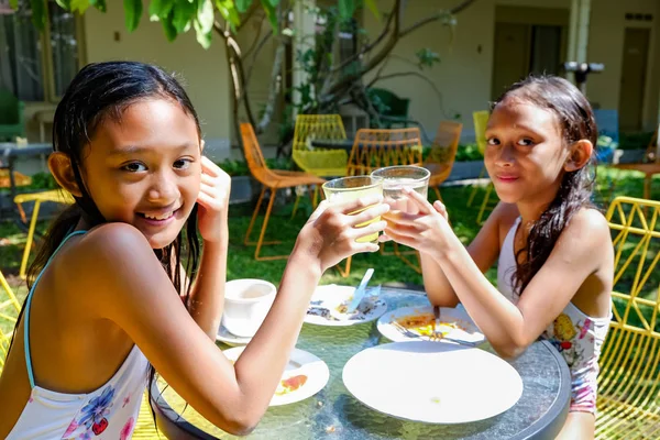 Duas meninas asiáticas de maiô tendo algumas refeições e bebidas e diversão juntos depois de atividades de natação — Fotografia de Stock