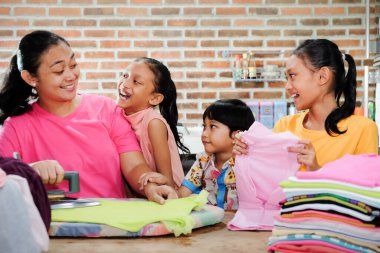Güneydoğu Asya Aile Yaşam Tarzı: Üç çocuğuyla çevrili giysileri ütülemekten mutlu bir anne olarak evde kalın. Aile Beraberliği