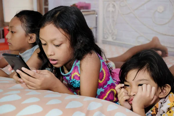 동남아시아의 소년은 여동생 스마트폰을 집중하는 느낀다 — 스톡 사진