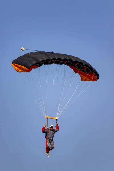 Paracaidista Descendiendo Con Paracaídas Rojo Contra Cielo Azul — Foto de Stock