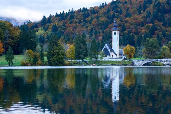 Torre de la iglesia y puente de piedra en el lago Bohinj —  Fotos de Stock