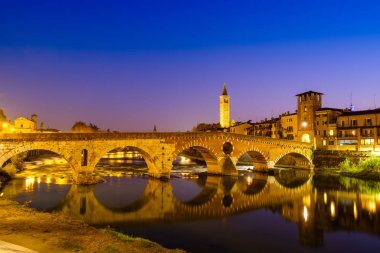 Ponte Pietra Adige Nehri geceleri vardır. Campanile di Santa Anastasia Verona arka planda görünür. 