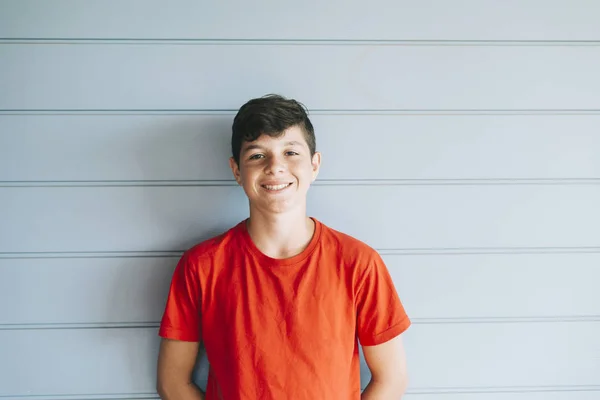 Portrait of a cheerful male teen leaning on wood wall while looking camera — Stock Photo, Image