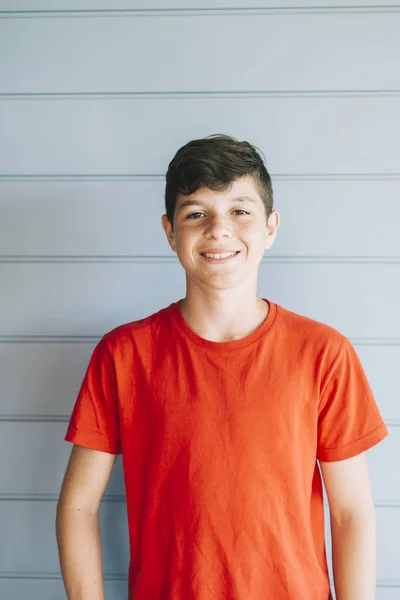 Portrait of a cheerful male teen leaning on wood wall while looking camera — Stock Photo, Image