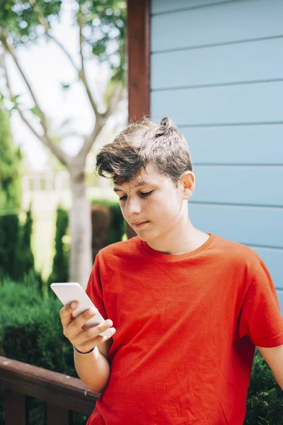 Perfil de um adolescente feliz macho mensagens de texto em um telefone inteligente — Fotografia de Stock
