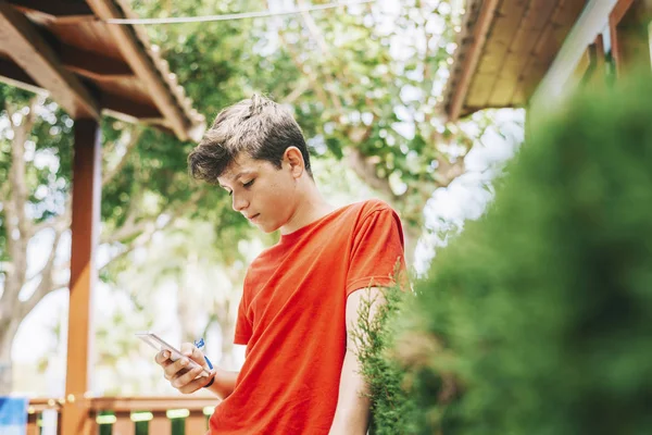 Profile of a happy male teen texting on a smart phone — Stock Photo, Image