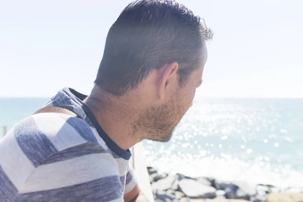 Vista trasera de un hombre sentado en el paseo marítimo mirando al horizonte — Foto de Stock