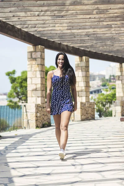 Mulher hispânica bonita em vestido azul em pé ao ar livre enquanto olha para a câmera — Fotografia de Stock