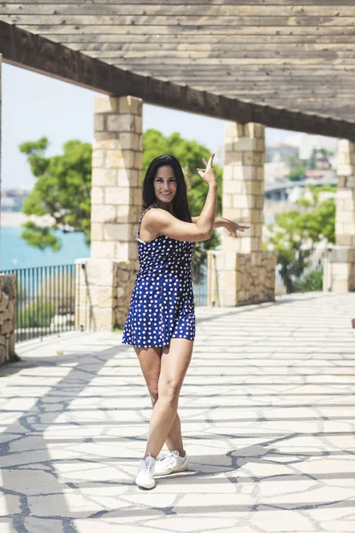 Hermosa mujer hispana en vestido azul de pie al aire libre mientras mira la cámara —  Fotos de Stock