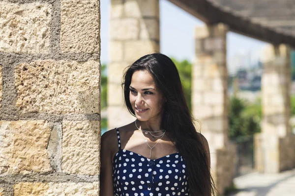 Mulher hispânica bonita em vestido azul inclinado na parede enquanto olha para longe — Fotografia de Stock