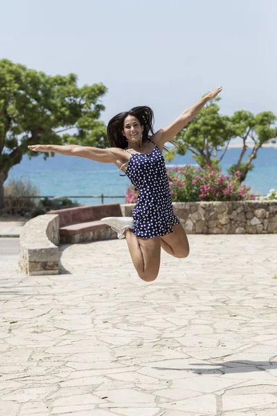Mooie latino vrouw in blauw jurk springen buiten — Stockfoto