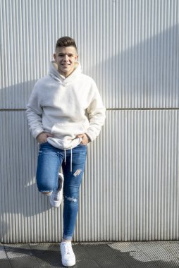 Duvara yaslanmış, elleri cebinde genç bir erkek portresi.
