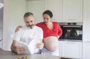 Gülümseyen çift mutfakta bir kitaba danışıyor..