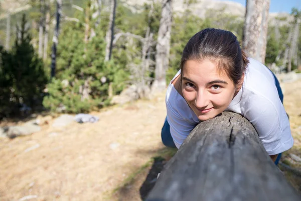 Genç Kız Ormanda Kameraya Bakarken Bir Kütüğe Tutunmuş — Stok fotoğraf