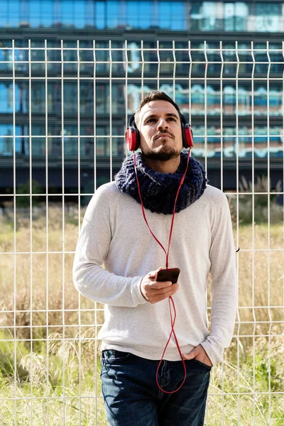 Ung Skäggig Man Med Hörlurar Och Hålla Smartphone Medan Lutar — Stockfoto