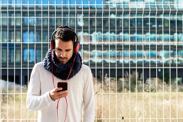 Ung Skäggig Man Med Hörlurar Och Hålla Smartphone Medan Lutar — Stockfoto