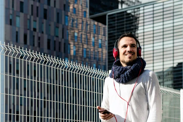 Ung Skäggig Man Med Hörlurar Och Hålla Smartphone När Går — Stockfoto